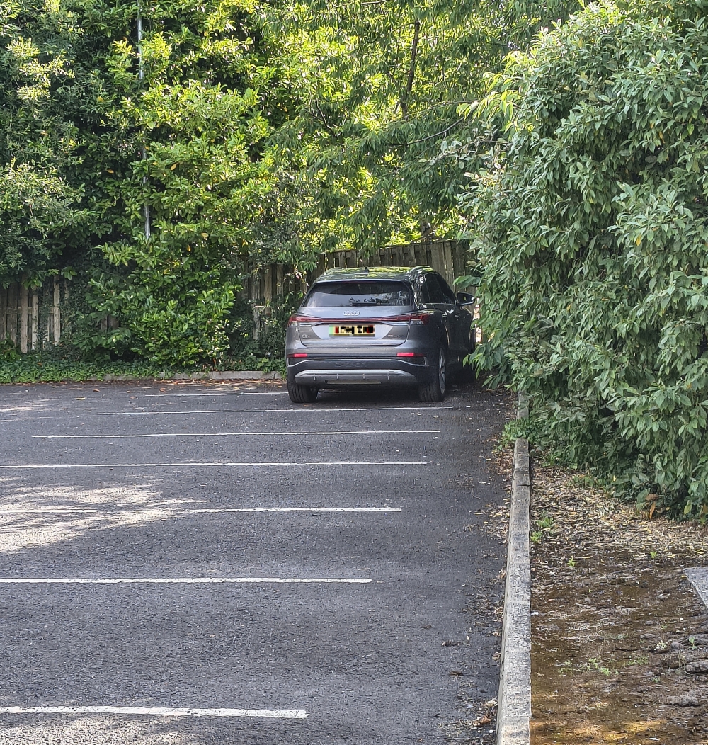 A car either parked badly or dumped in the corner of a carpark.