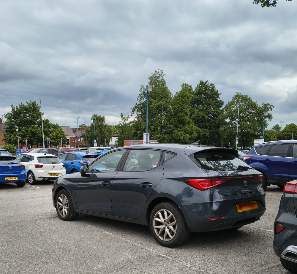 A badly parked car with a dent on the back